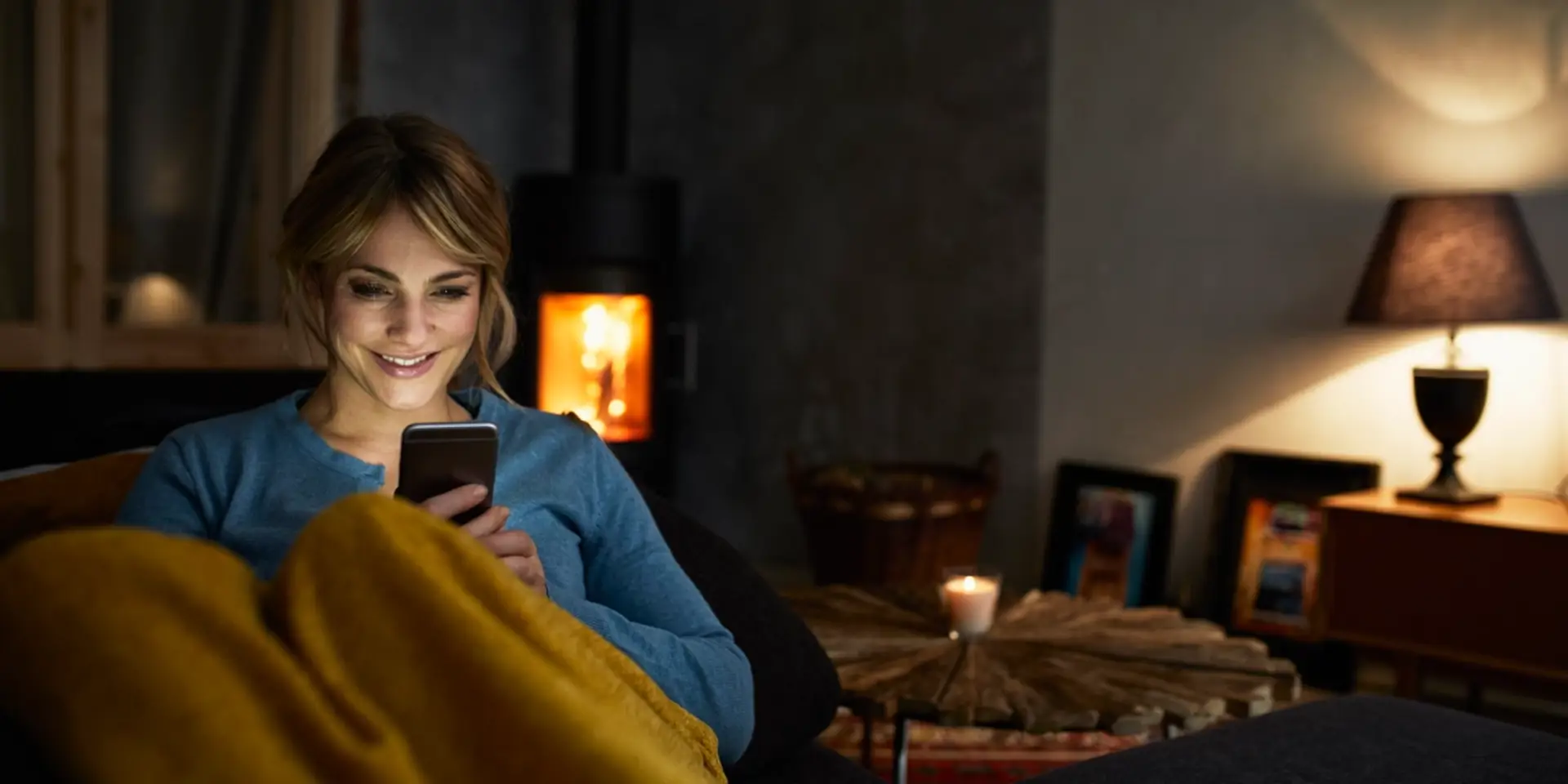 Kvinna sitter hemma i soffan med sin mobil och pratar med Lexly om juridiska frågor