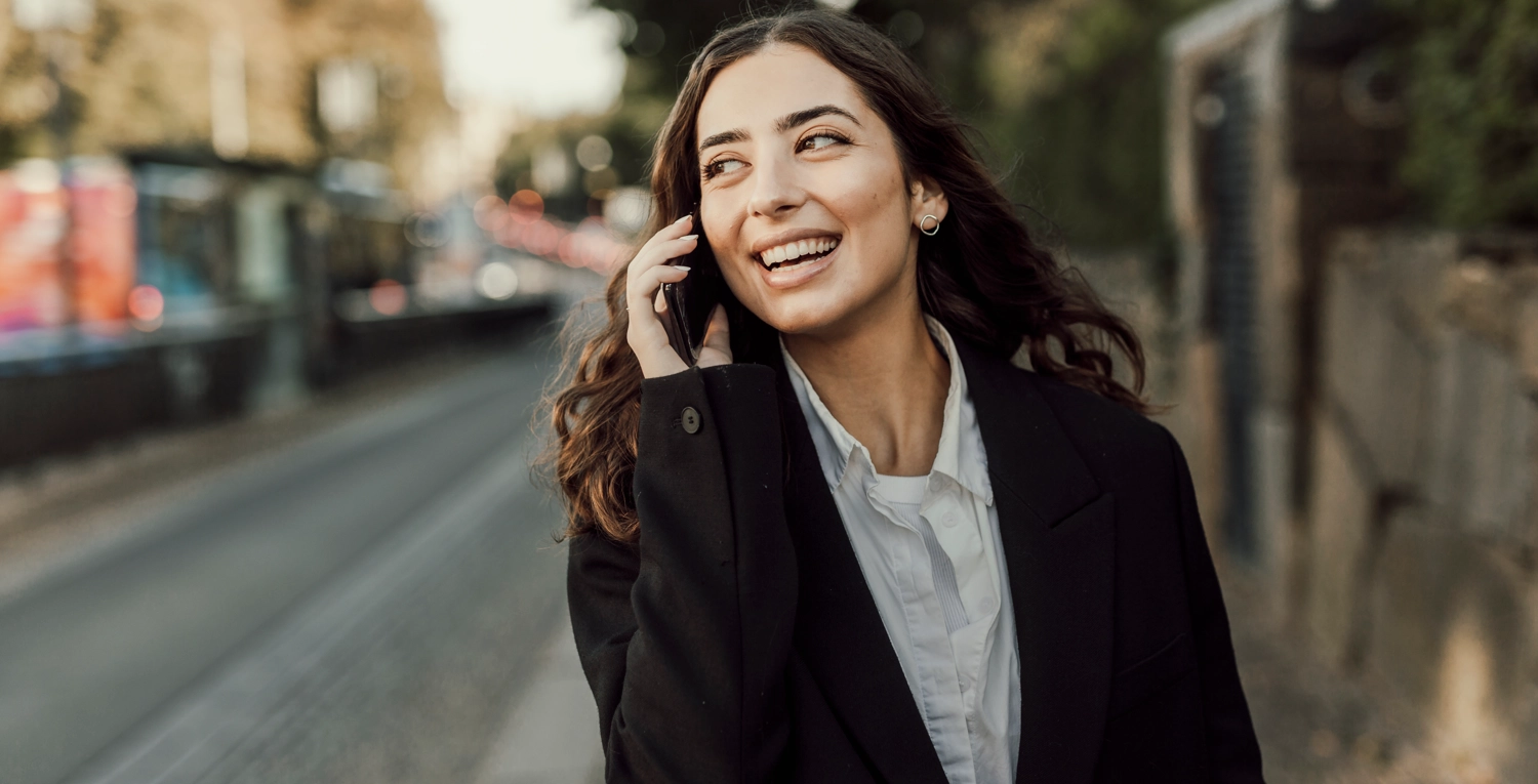 Kvinna pratar i mobiltelefon, går på trottoar ingångslön ökar