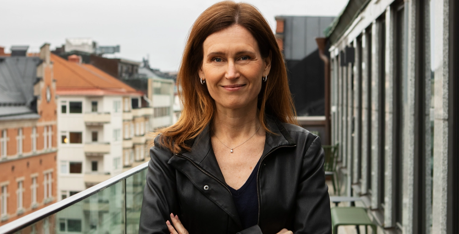 Kvinna med mörkt hår, svart jacka, armarna i kors.