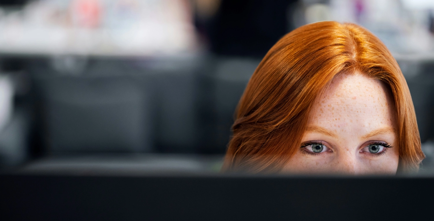 En kvinna med rött hår tittar på en dataskärm övervaka anställda