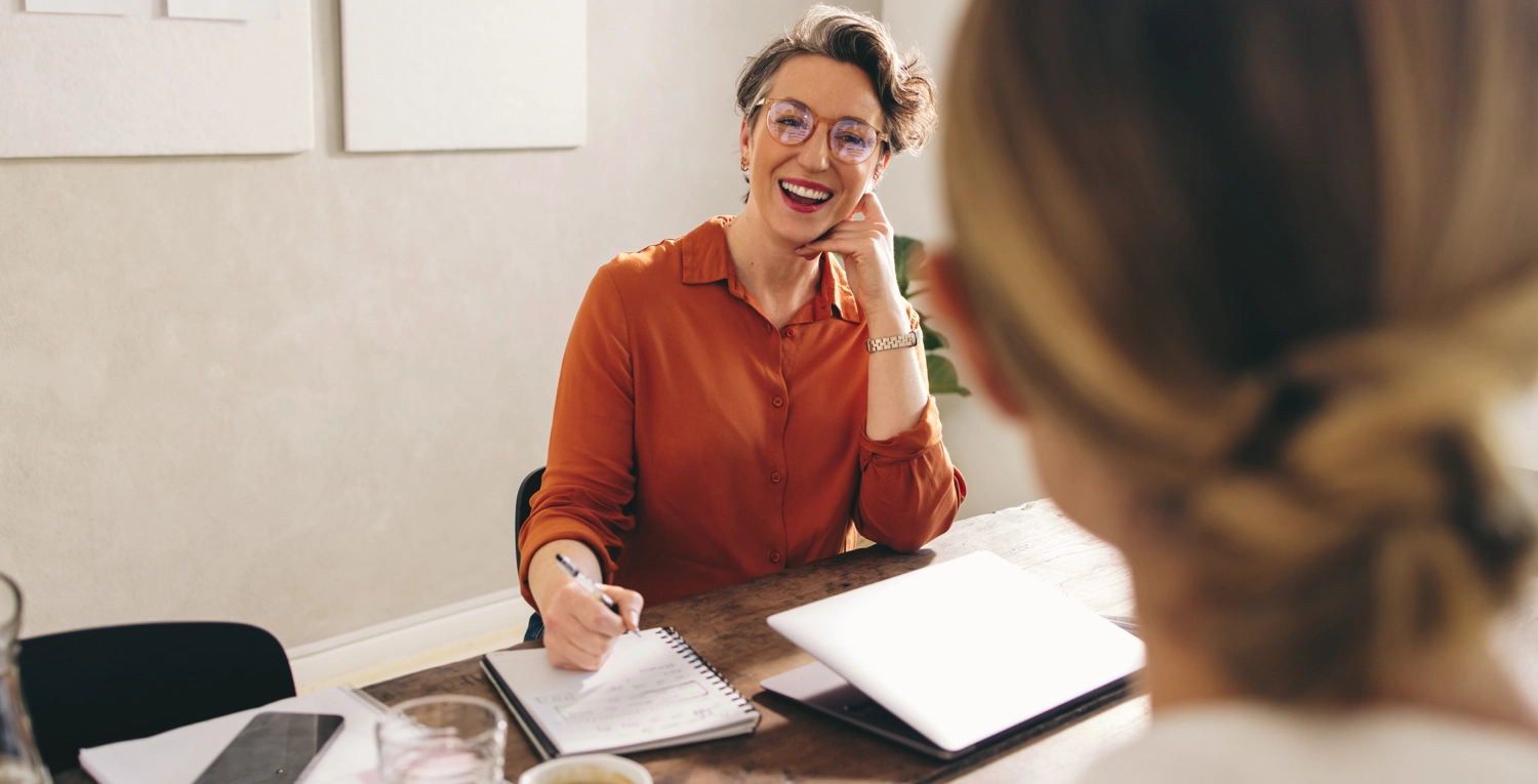 Två personer i möte, chef i orange blus psykologiska metoder vid löneförhandling