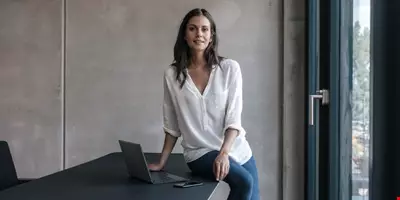kvinna med vit blus sitter på skrivbordskanten