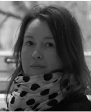 Porträttbild på kvinna med axellångt hår och allvarlig min, hon har en prickig scarves om halsen.